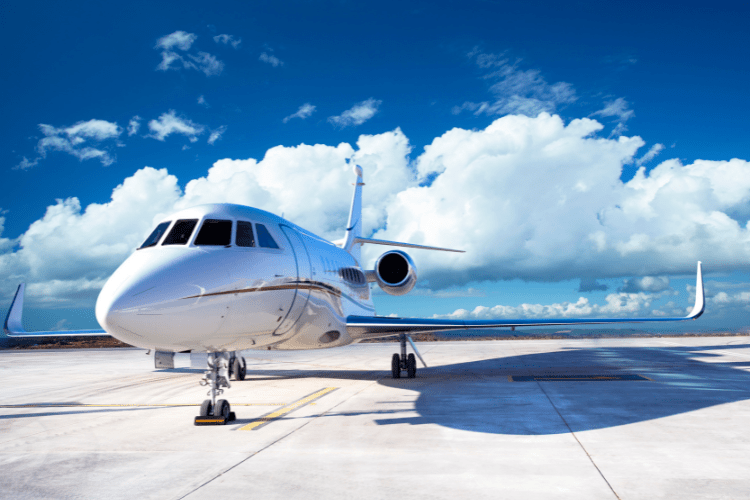 Private jet on the runway against a blue sky with white fluffy clouds