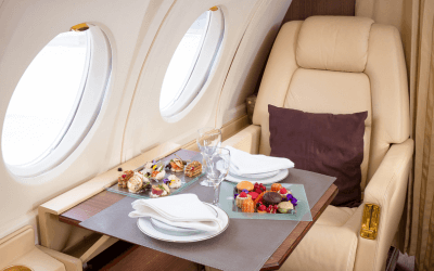 Flight attendant serving refreshments to passengers inside a chartered airplane, highlighting the comfort and convenience of group air travel for corporate summer retreats.